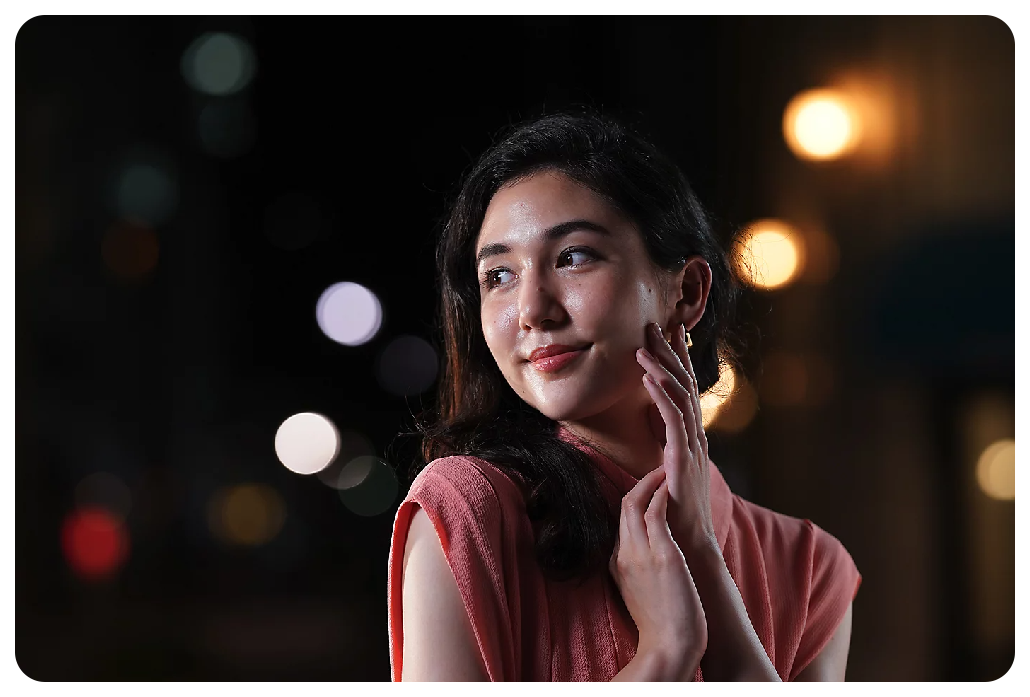Sony A7C Sample image of black haired woman wearing soft pink dress standing in the street at night