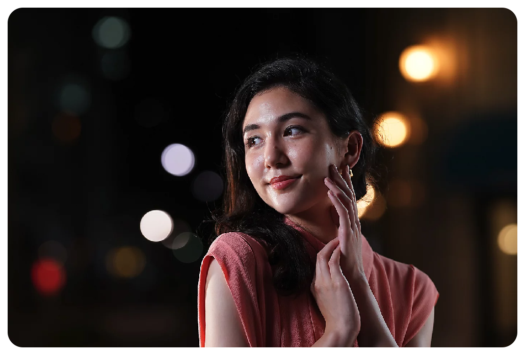 Sony A7C Sample image of black haired woman wearing soft pink dress standing in the street at night