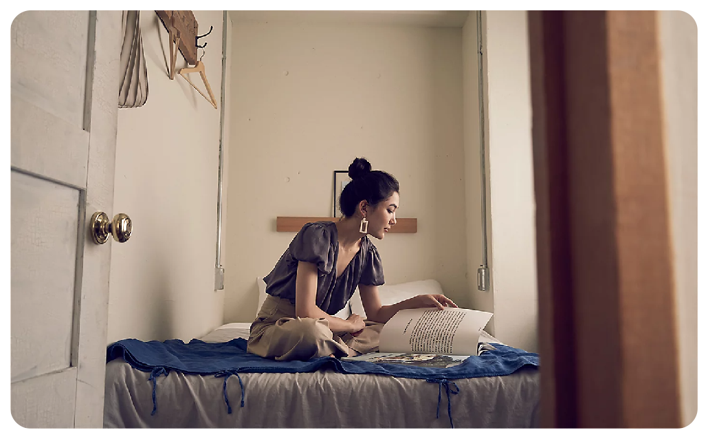 Sony A7C preview of woman sat reading newspaper on her bed