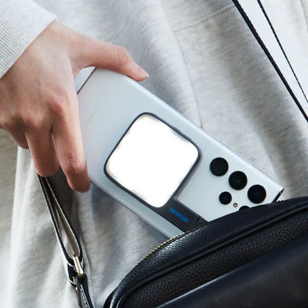 someone pulling a smart phone out a bag with the amaran go light on the back