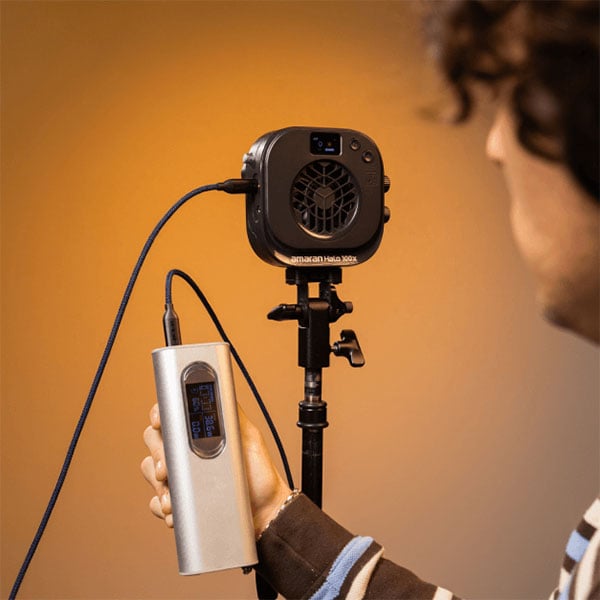 someone holding a power bank connected to the amaran monolight