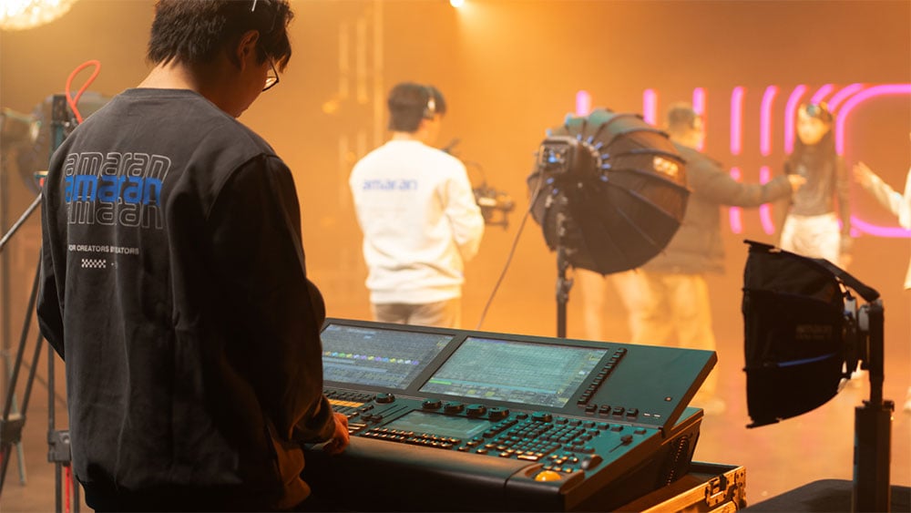 someone controlling the amaran monolight using dmx controls behind a control desk in a studio