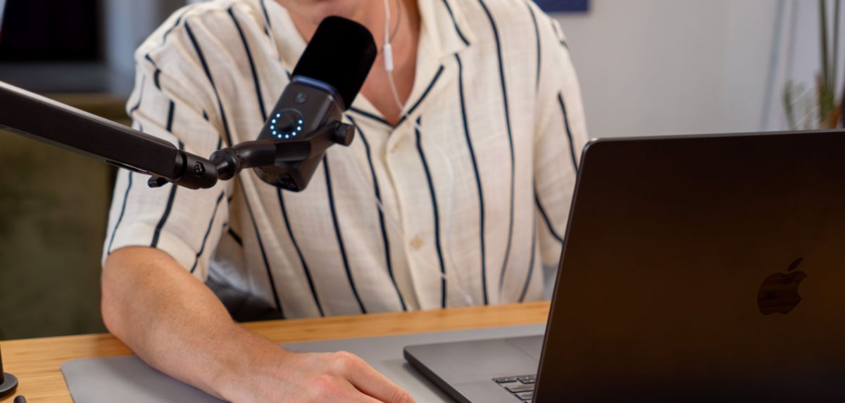 black amaran mic on a mic arm with someone working on a laptop