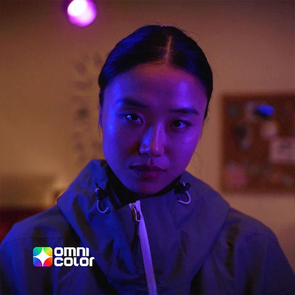 a woman with a blue light in her face with the omnicolor logo
