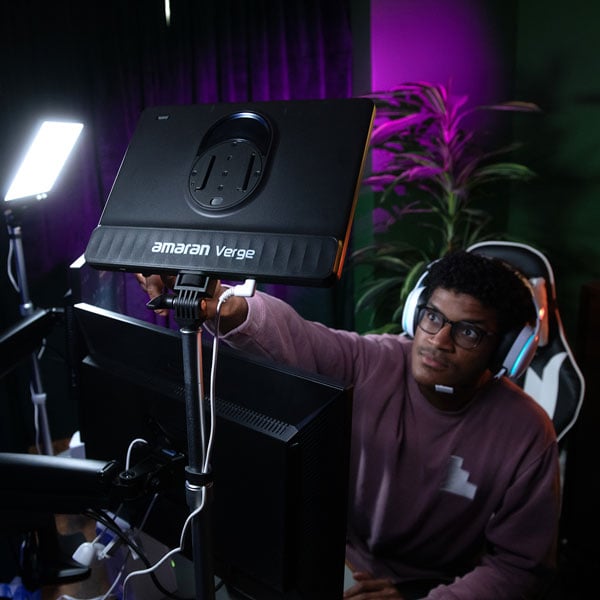a streamer adjusting the amaran verge panel light attched to the back of his monitor