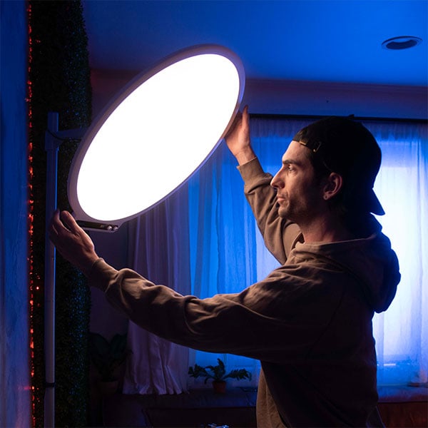 someone adjusting the amaran panel light on set