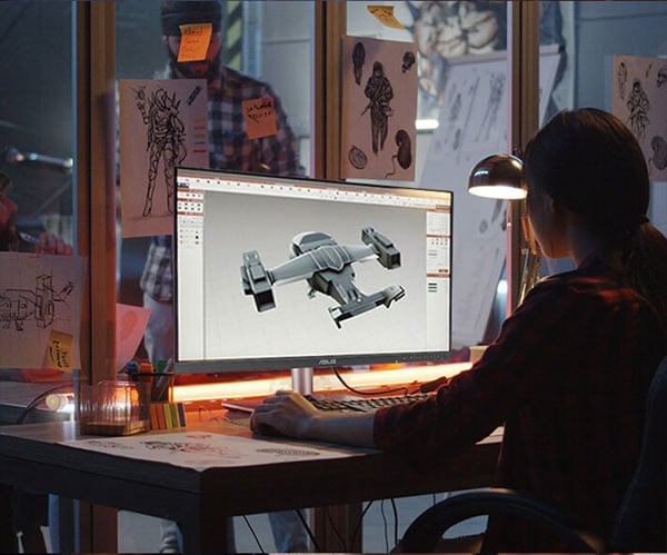 games developer sat at a desk 3d modelling a space ship on a asus pro monitor