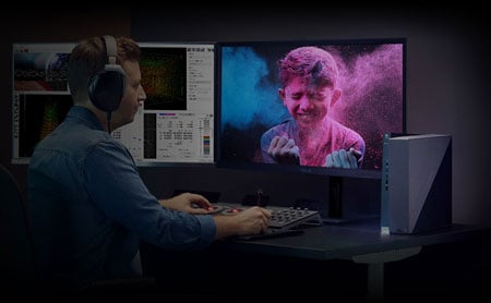Man sat a desk with 2 asus proart monitors and a vibrant blue and pink photo