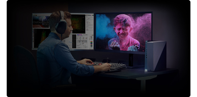 Man sat a desk with 2 monitors and a vibrant blue and pink photo