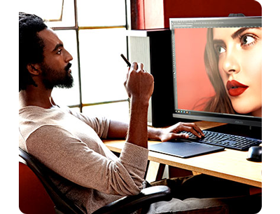 colourist sat working at his desk with a female portrait photograph open on a monitor