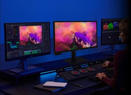Colourist with a three asus proart displays setup and colour grading wheels