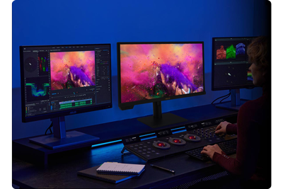 Colourist with a three monitor setup and colour grading wheels