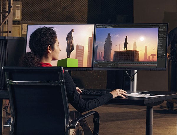 a woman sat a desk editing film footage on two asus pro art monitors