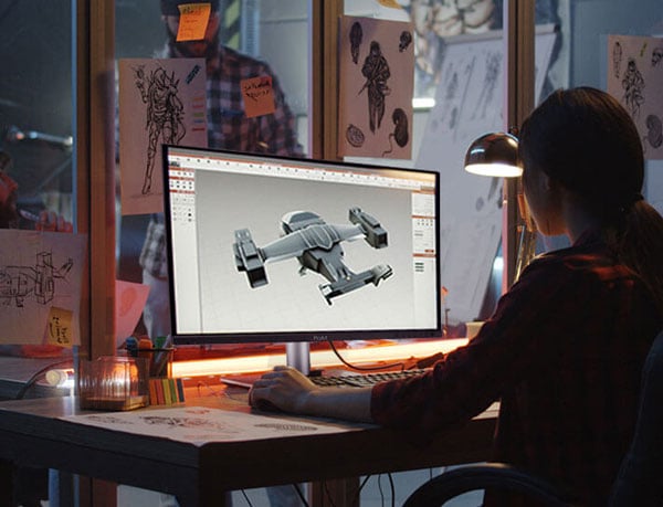 a man sat a desk 3d modelling a space ship on a asus pro art monitior