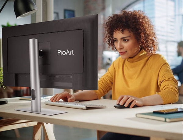 a man sat a desk editing a design on the asus proart monitor