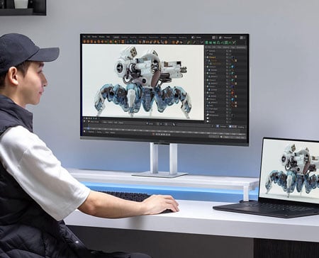 someone working on a mech 3d model with a laptop connected to the asus proart display