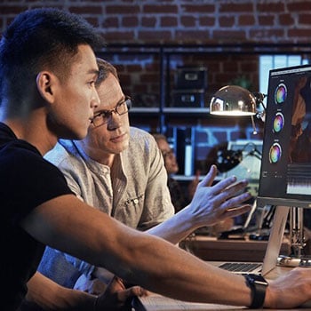 Two colourists working together grading video footage at a ProArt display