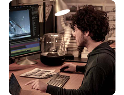 image of man with curly brown hair, wearing grey jumper video editing using ASUS ProArt displays