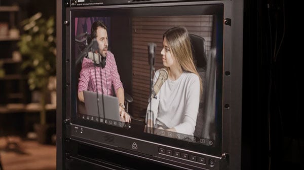 Atomos Shogun AV-19M 19-inch 4K HDR rackmount monitor displaying a live dual-person podcast interview feed in a professional broadcast studio setup