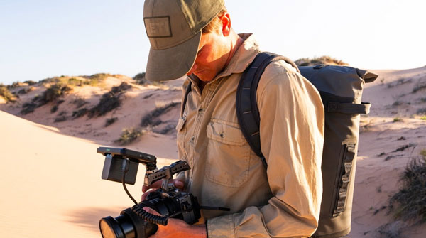 someone looking at the atomos shinobi 7 attached to a camera