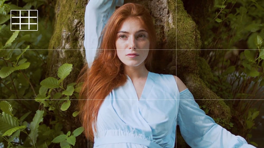a woamn with red hair lent against a tree with a monitor grid overlayed on top of the image