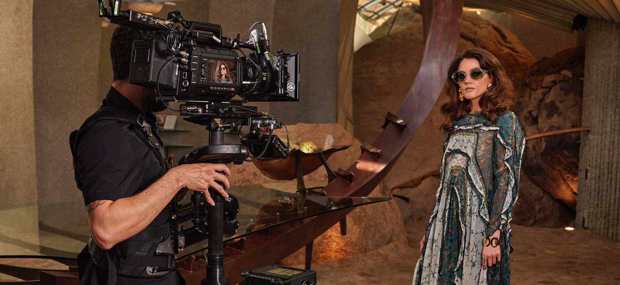 camera operator with URSA Cine 12K on steady cam rig recording actress standing in desert cave room