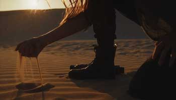 actor with sand flowing through fingers standing in the desert captured in slow motion