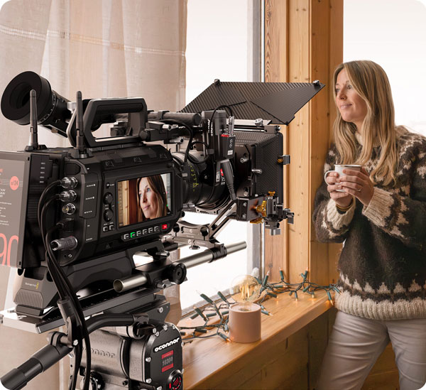 a woman being filmed holding a cup of coffee in a window using the blackmagic ursa cine