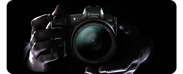 close up front view of the canon r camera held in 2 hands on a black background