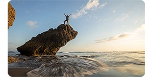 man on a cliff surrounded by the ocean taken with the canon 35mm lens