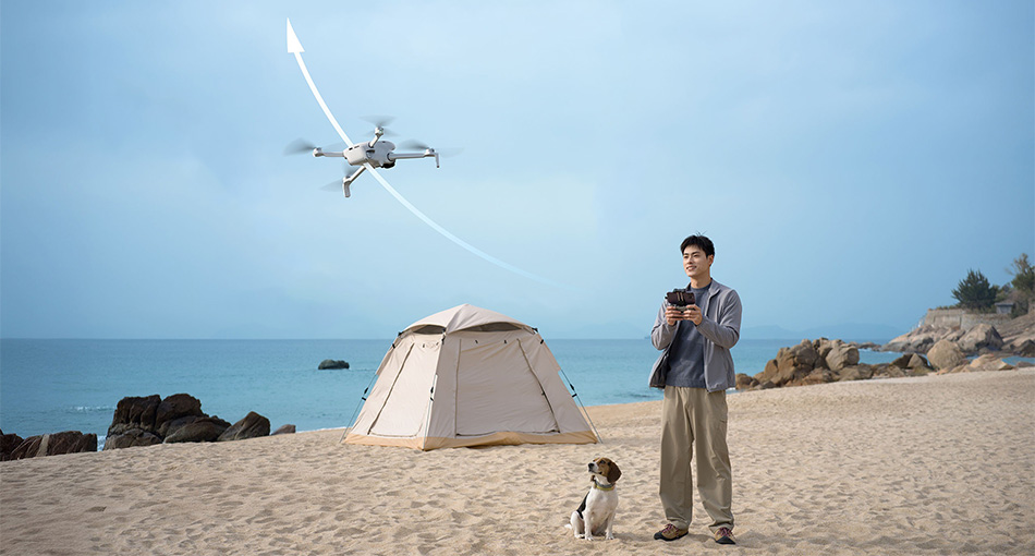 a man with a dog camping on a beach flying the dji lito 1