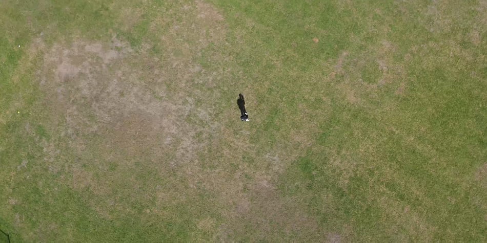 top down shot of a man stood in the middle of a field