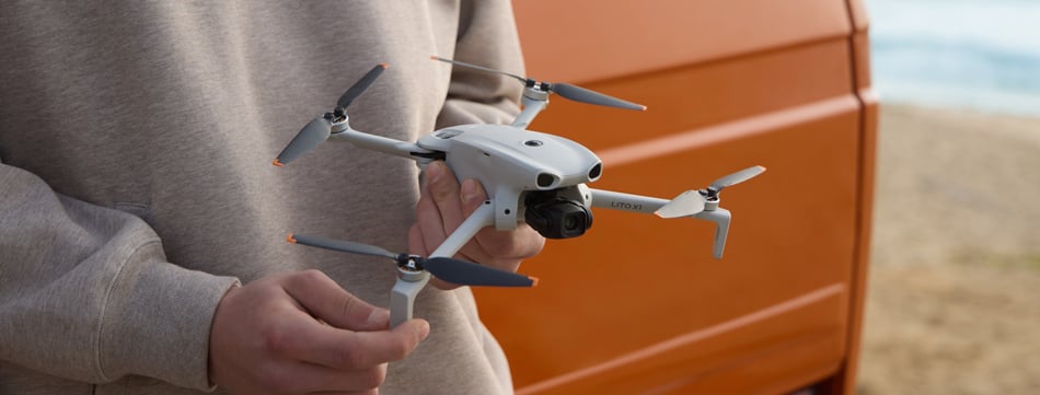 someone holding the dji lito x1 in front of a orange truck