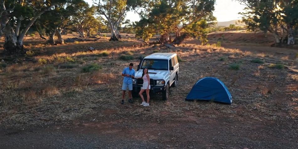 a man and woman leanrt against a car with a tent
