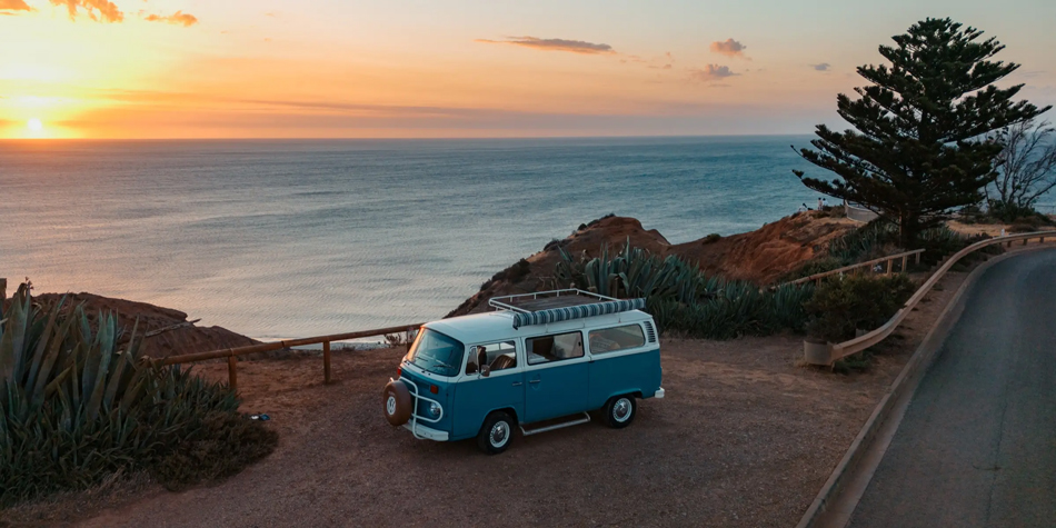sample image of a camper van packed next to a beach at sunset