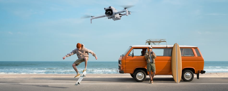 someone filming a skateboarder while lent against an orange camper van next to a beach using the dji lito x1