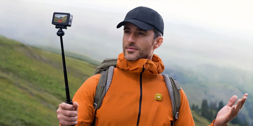 a man on a mountsin side using the dji osmo action 6 and mic mini 2