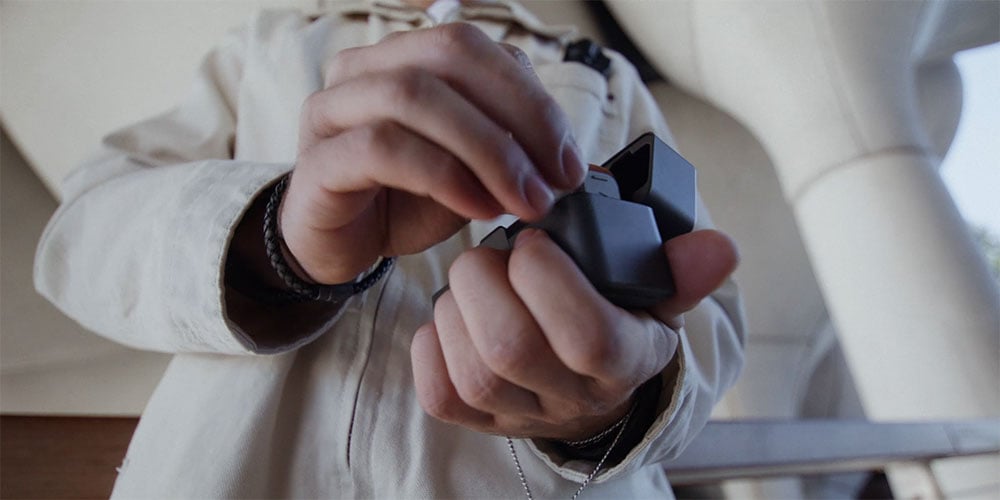 close up of someone putting the dji mic mini 2 into the charging case