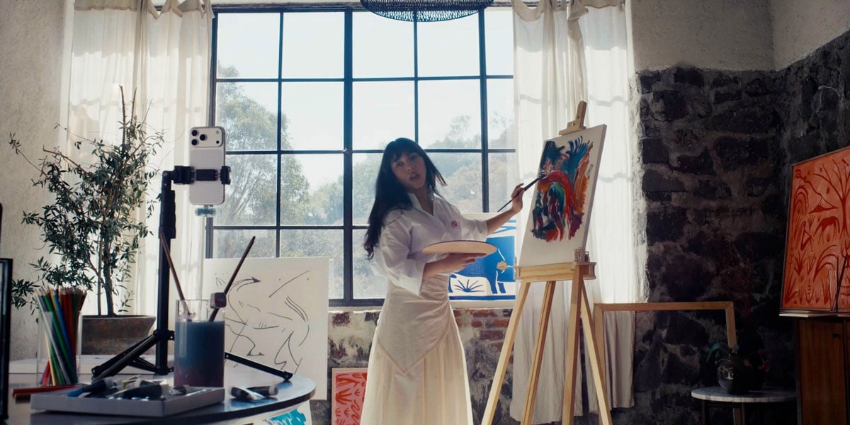 a woman filming while painting a picture