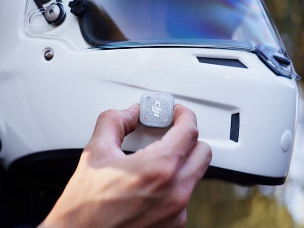 Someone attaching the dji mic mini 2s to the side of a helmet