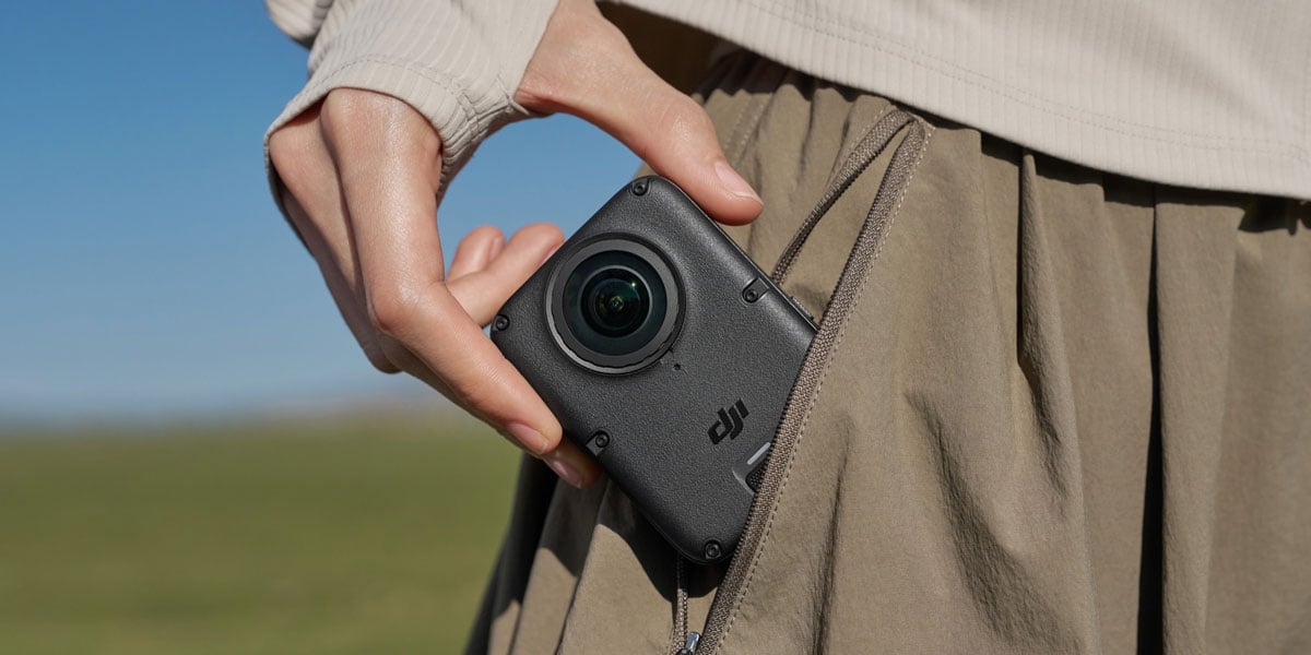 A person slipping a compact DJI action camera into their pocket while outdoors