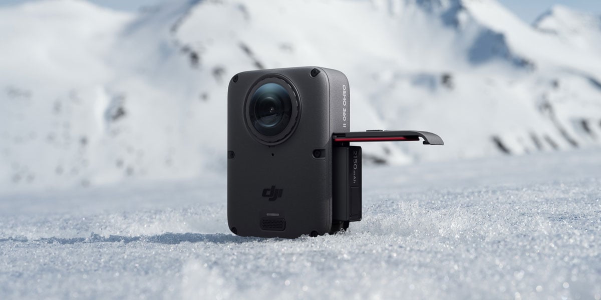 DJI Osmo 360 II action camera sitting on white snow with mountains in the background