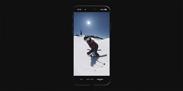 Smartphone displaying a video of a person skiing down a snowy mountain slope under a bright sun