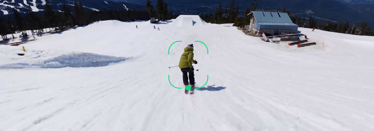 Skier wearing a green jacket riding down a snowy ski resort slope being tracked using the dji osmo 360 II