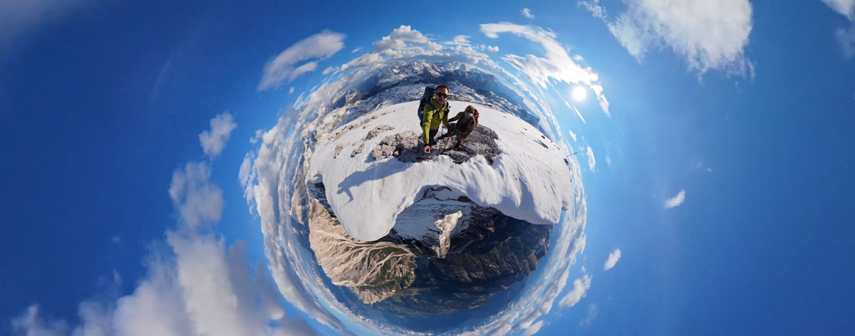 a 360-degree little planet panoramic photo of climbers on a snowy ridge