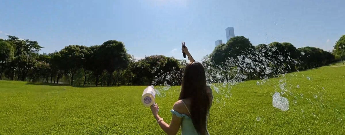 sample image of a woman using a bubble blaster toy in a park