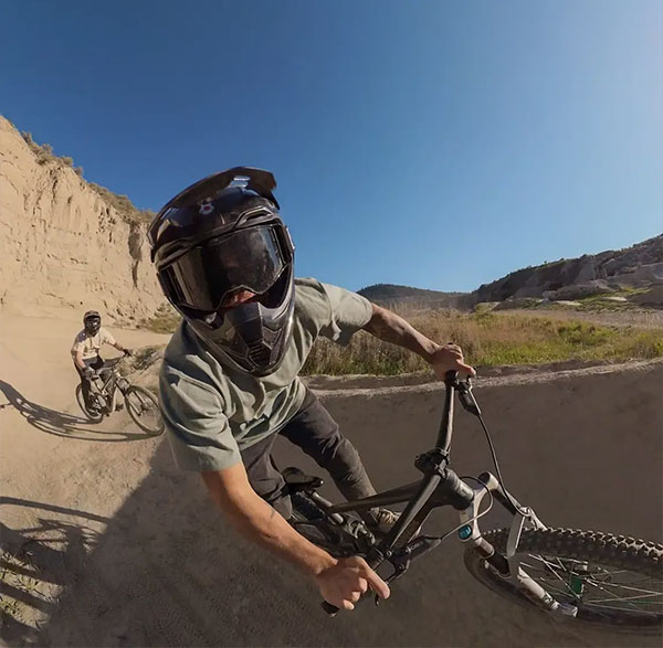 Mountain biker wearing full-face helmet and goggles riding on a dirt track