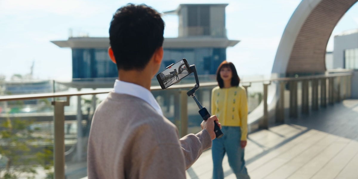 a man filming a woman on a bridge using the ptf mode of the osmo mobile 8p