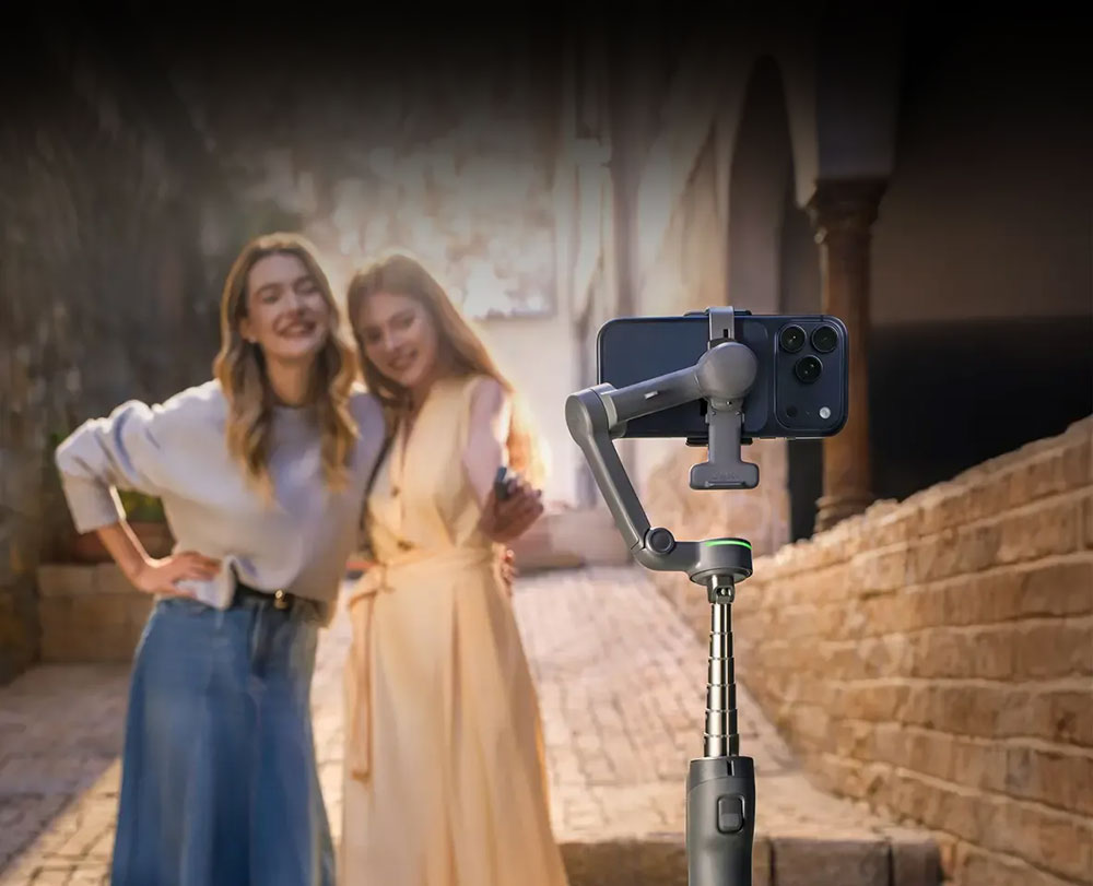 two women taking a photo with the osmo mobile 8p using the built-in extension rod