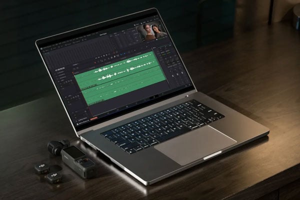 dji osmo pocket 4 on a desk next to a laptop showing the recorded audio